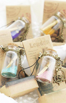 Small glass bottles filled with colorful sand, decorated with charms and tags.