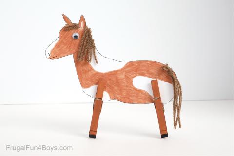 This is a photo of brown horse made of clothespins, paper, yarn, and googly eyes against a white background