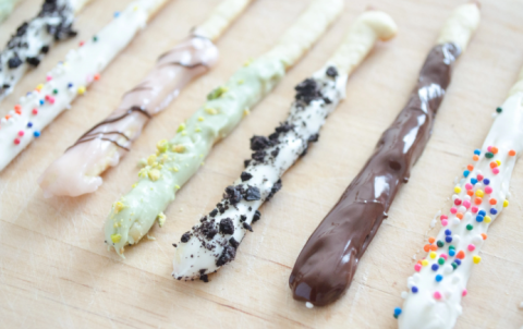 Varied types (chocolate, vanilla with sprinkles, vanilla with chocolate drizzle, cookies and cream, and matcha) of homemade pocky sticks lined up on a tray