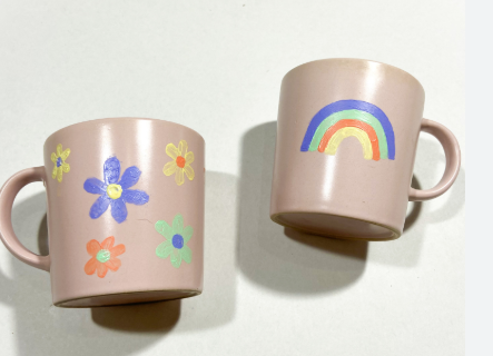 Two beige painted mugs (one with flowers and one with a rainbow)