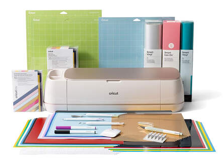 This picture is a photograph of a Cricut machine surrounded by Cricut supplies, including cutting tools, paper, and mats