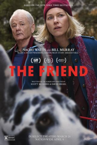Promotional artwork for the film The Friend. In the foreground, a large black-and-white dog is shown slightly out of focus, facing the viewer. Behind the dog stand two adults outdoors: a woman wearing a red knit hat, scarf, and blue coat, and an older man wearing a dark coat and scarf. Both look forward with neutral expressions. The background shows trees and a natural setting. Large red text across the center reads “The Friend.” Smaller text above and below includes cast names and release information.