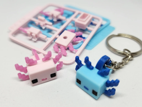 2 minecraft style axolotl keychains and 2 flat kits of the parts. One set is dark and light pink and the other is light and dark blue.