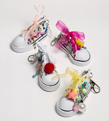 4 white high top key chains decorated with ribbon, beads, puffs, and colorful paint or markers