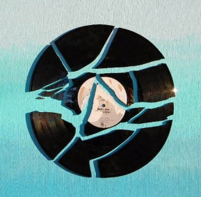 broken black record pieces glued to a canvas painted with a blue gradient
