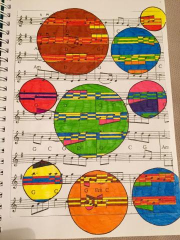 A piece of sheet music with painted multicolor circles of varying sizes and colors