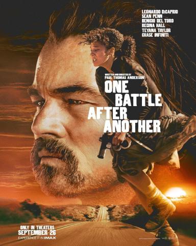 A dramatic movie poster for One Battle After Another shows a large close-up of a man’s face in the background, looking serious against a sunset sky. In the foreground, a woman runs along a road holding a handgun, her hair blowing behind her. The scene is set in a desert landscape with a glowing sun near the horizon. Text includes the title “One Battle After Another,” cast names, and “Only in Theaters September 26.”