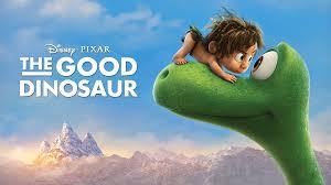 A bright animated movie poster for The Good Dinosaur shows a large green dinosaur with a gentle expression looking upward while a small boy lies on top of its head, smiling and peering over. Snow-capped mountains and a soft blue sky fill the background. Text at the top reads “Disney Pixar The Good Dinosaur.”