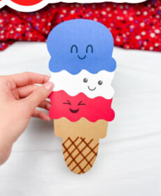 a photo of a red, while, and blue ice cream cone made of paper with happy faces on each scoop