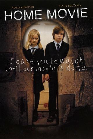 A dark, unsettling movie poster for Home Movie shows two children standing side by side in a doorway, dressed in formal school uniforms and staring forward with serious expressions. The surrounding walls are covered with eerie childlike drawings. Text at the top reads “Home Movie,” and handwritten-style text across the center reads, “I dare you to watch until our movie is done.”