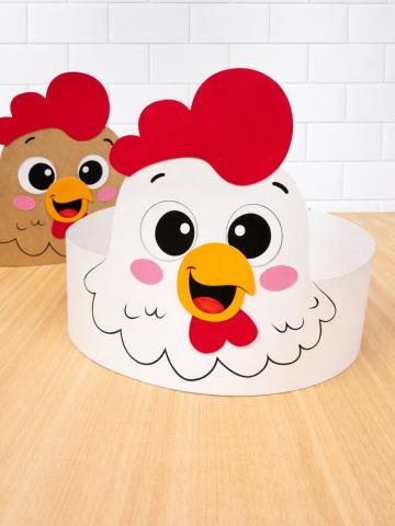 The image depicts a paper head band in the shape of a chicken that has been assembled and resting on a table. 