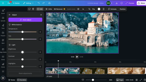A video editing interface is shown on a computer screen. On the left, an “Adjust” panel includes sliders for white balance, temperature, tint, brightness, contrast, and highlights. In the center, a preview displays a coastal town built into cliffs beside turquoise water, with an arched structure extending over the sea. Below, a timeline shows video clips and a playhead near the start. Editing tools and menu options appear across the top.
