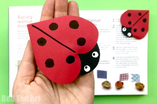 person holding a heart shaped paper ladybug in their hand as a valentine