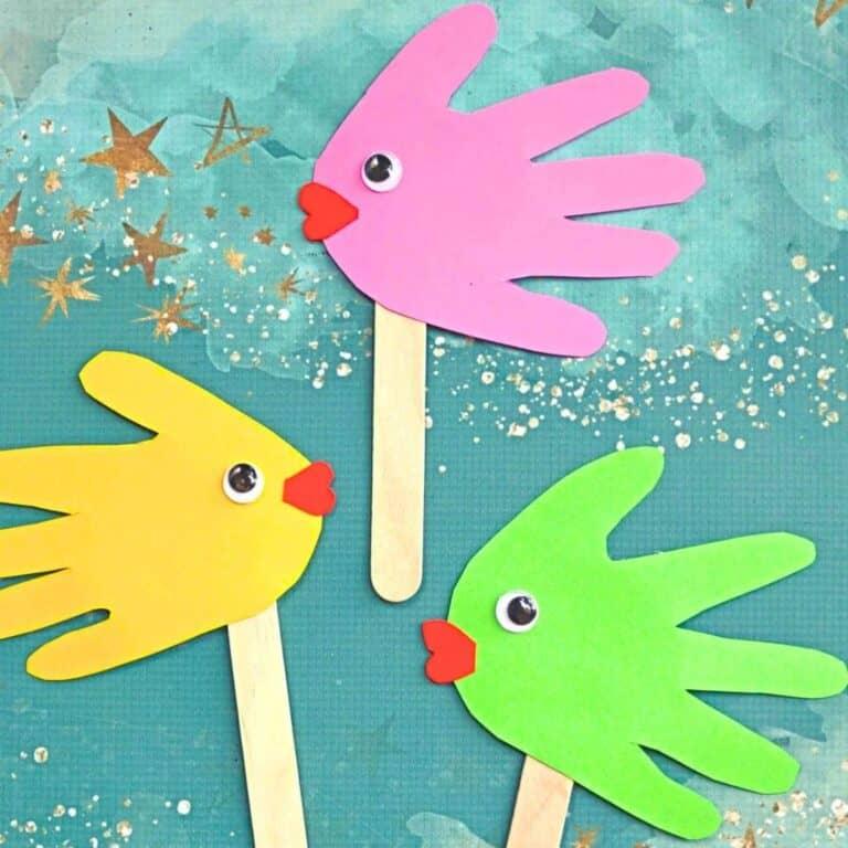 a photo of pink, green, and yellow handprint fish with googly eyes and popsicle sticks