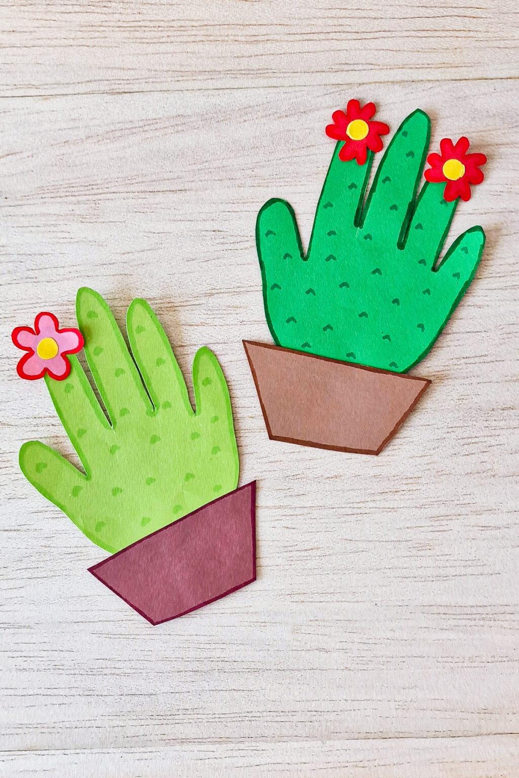 a photo of two green handprints decorated to look like cacti in a brown paper pot
